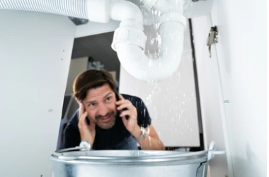 A man describing a leaking pipe to someone on the phone